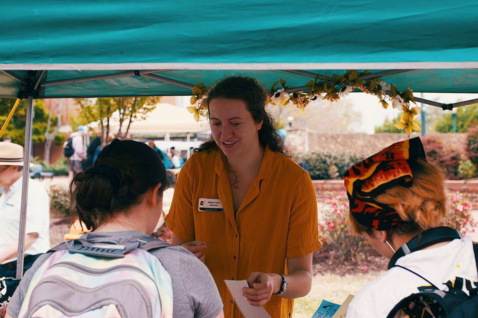 A nonprofit staffer helps visitors at a community event.